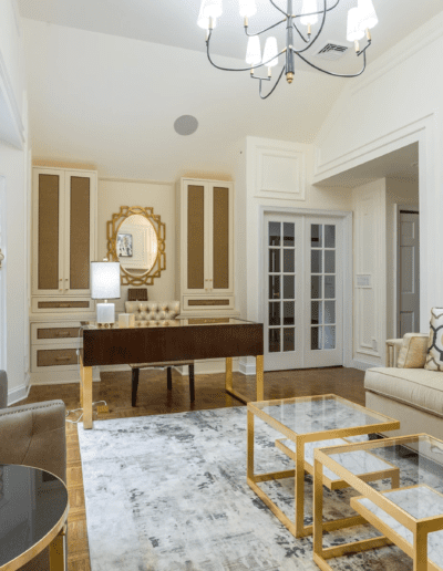 An elegant living room with beige and gray furnishings, gold accents, and a chandelier.