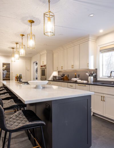 A spacious modern kitchen with a large island, white cabinetry, and brass light fixtures.